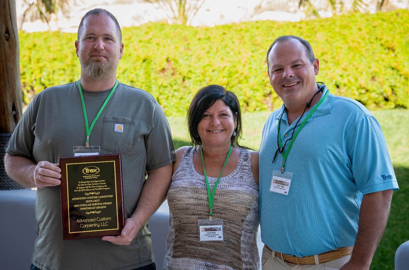 Three smiling people, one holding award